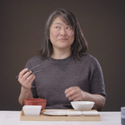 a lady looks perplexed while eating with chopsticks