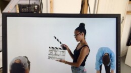 a camera assistant holds a clapper board in a white studio