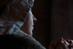 A woman in 17th Century clothing is praying