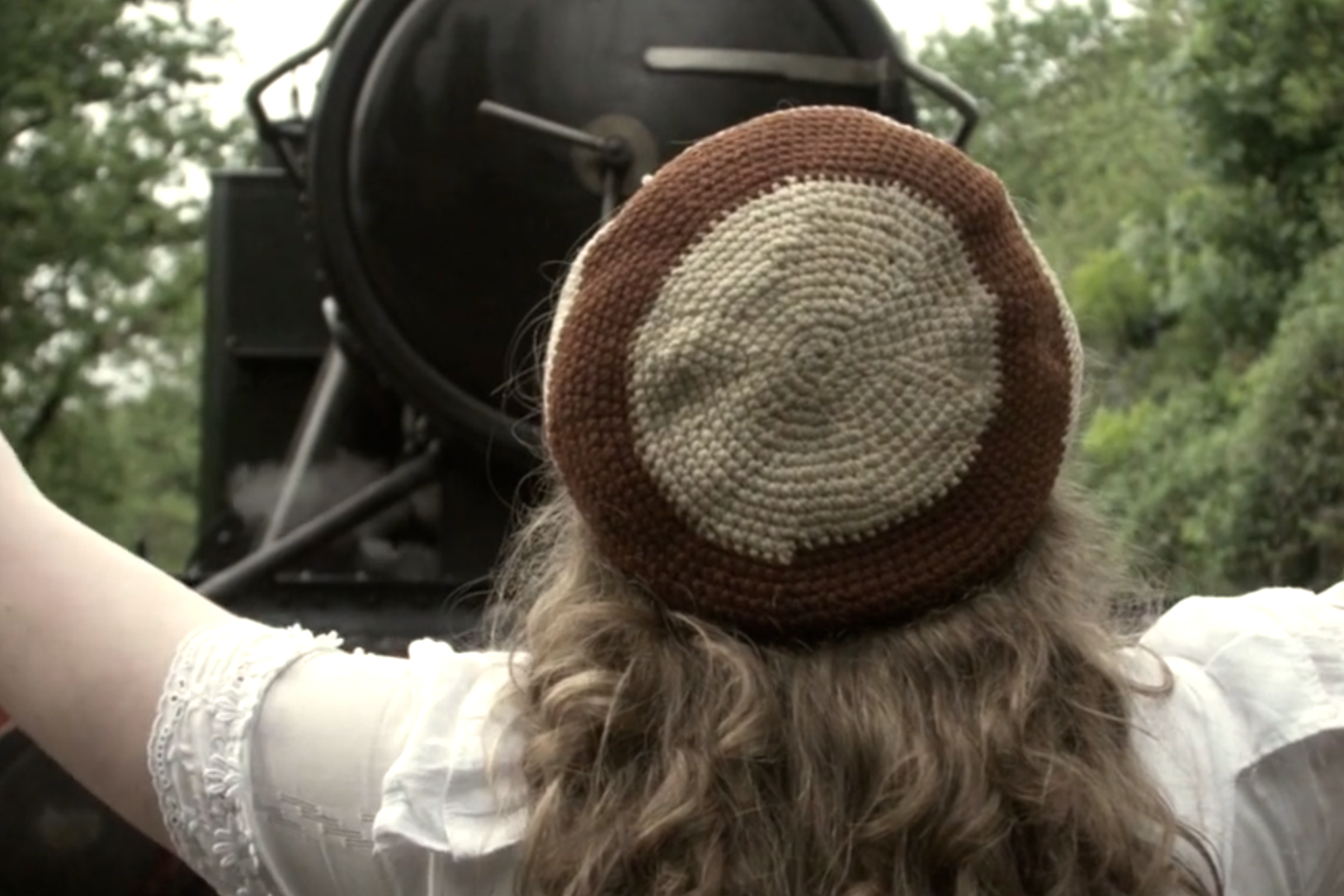 A brave girl stands in front of a steam train
