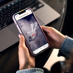 A woman's hands hold an iphone and we can see the Preston Street Films website on the screen.