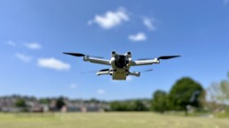 A Drone BTS shot of a drone hovering above a field on a summer day