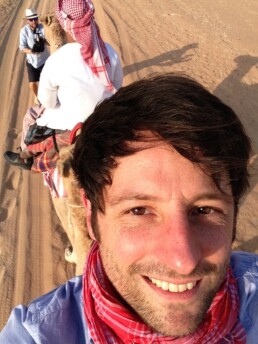 Chris Jones riding backwards on a camel in dubai