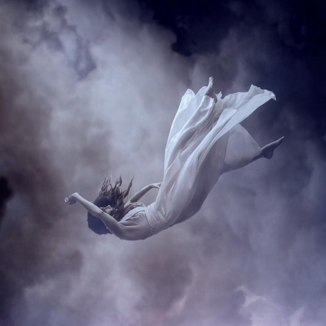 a woman in a flowing dress falls through clouds
